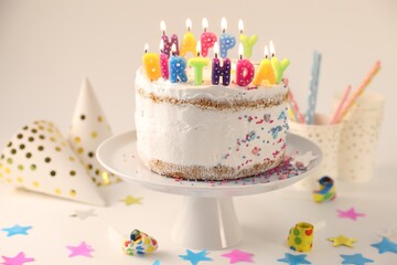 Tasty Birthday cake with burning candles and party decor on white table