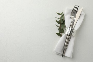 Stylish setting with cutlery and napkin on white textured table, top view. Space for text