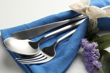 Stylish setting with cutlery and napkin on white textured table, closeup