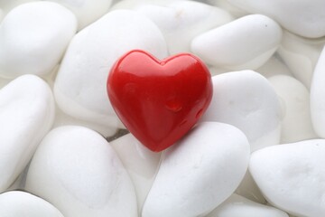 Obraz premium Red decorative heart on stones and water, top view