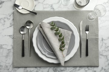 Stylish setting with cutlery, glasses and plates on white marble table, flat lay