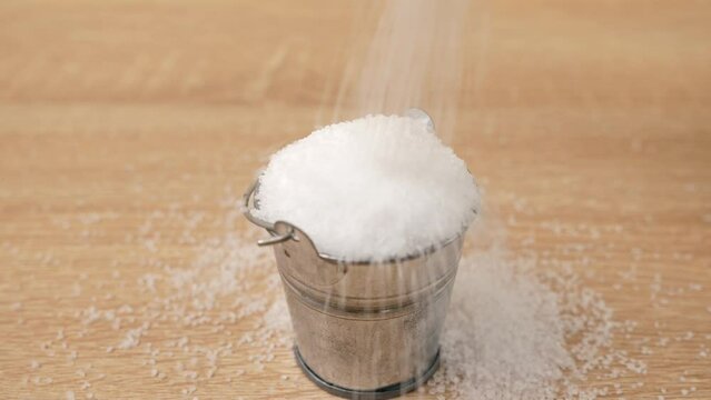 Salt is poured into a small metal bucket. Abuse of salt.