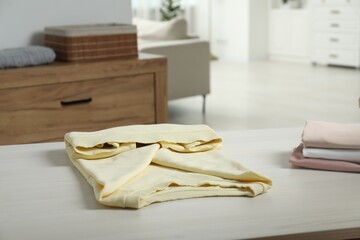 Different folded clothes on white wooden table at home