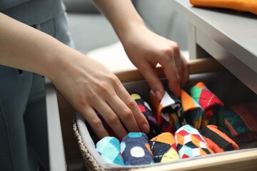 Woman putting socks into drawer indoors, closeup
