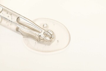 Glass pipette and transparent liquid on beige background, closeup. Space for text