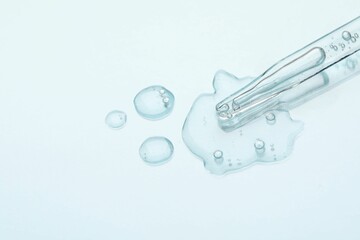 Glass pipette and transparent liquid on light background, top view. Space for text