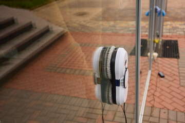 A robotic white Automotive tire is cleaning a glass window