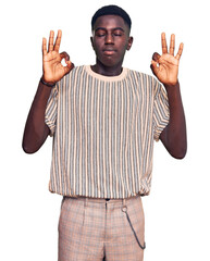 Fototapeta premium Young african american man wearing casual clothes relax and smiling with eyes closed doing meditation gesture with fingers. yoga concept.