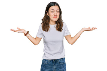 Young beautiful woman wearing casual white t shirt clueless and confused expression with arms and...