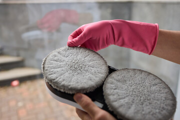 A robotic white Automotive tire is cleaning a glass window replacing cleaning cloths