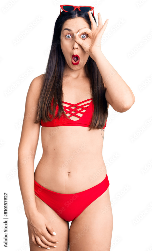 Poster Young beautiful caucasian woman wearing bikini doing ok gesture shocked with surprised face, eye looking through fingers. unbelieving expression.