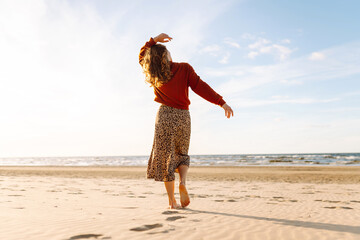 Beautiful woman walks along a picturesque sandy beach at sunset. Travel, weekend, relax and...