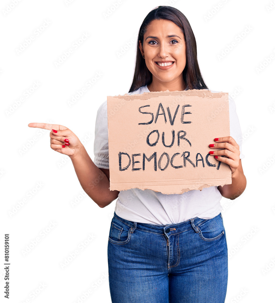 Poster Young beautiful woman holding save our democracy cardboard banner smiling happy pointing with hand and finger to the side