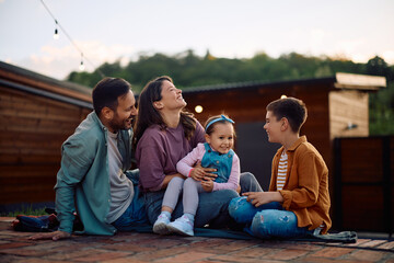 Happy parents having fun with their kids while relaxing in backyard.