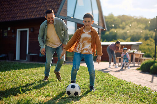 Little boy playing soccer with his father in backyard.
