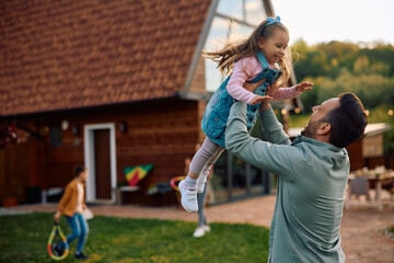 Playful father and daughter having fun in backyard,
