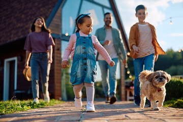 Little girl and her family walking with their dog outdoors.