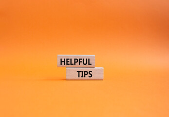 Helpful tips symbol. Wooden blocks with words Helpful tips. Beautiful orange background. Business...