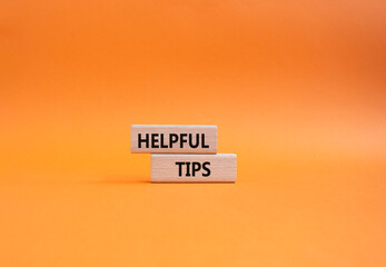 Helpful tips symbol. Wooden blocks with words Helpful tips. Beautiful orange background. Business and Helpful tips concept. Copy space.