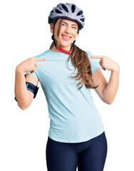 Beautiful caucasian young woman wearing bike helmet looking confident with smile on face, pointing oneself with fingers proud and happy.
