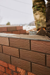 professional construction worker laying bricks and building barbecue in industrial site. Detail of hand adjusting bricks