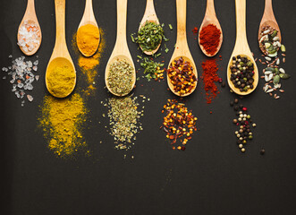 Various Asian spices in spoons on black background. Top view with free space