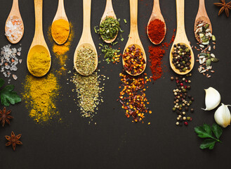 Various Asian spices in spoons on black background. Top view with free space