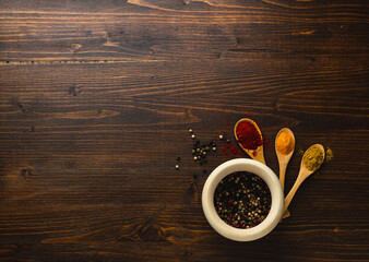 Various Asian spices in wooden spoons on wooden background. Top view