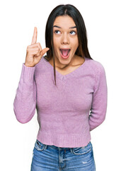 Young hispanic girl wearing casual clothes pointing finger up with successful idea. exited and happy. number one.