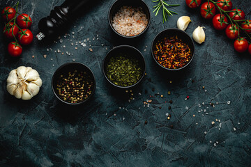 Dark stone kitchen background with spices, herbs and kitchen utensils. Free space for text. Top view. Rustic style.