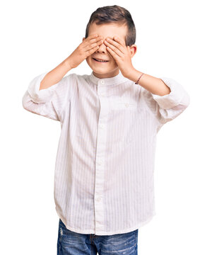 Cute blond kid wearing elegant shirt covering eyes with hands smiling cheerful and funny. blind concept.