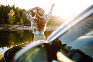 Young woman enjoying and having fun in their vacations outdoors leaning out car window. Summer trip.