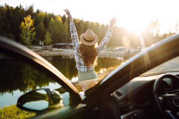 Young woman enjoying and having fun in their vacations outdoors leaning out car window. Summer trip.