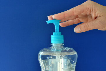 Person's hands applying washless hand sanitizer gel to help stop the spread of germs. blue...