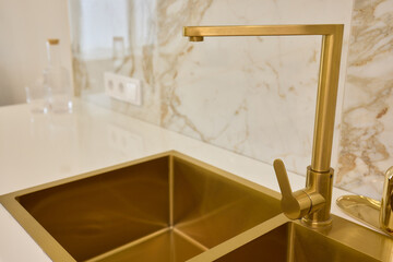 A gold faucet on a bathroom sink with a soap bottle