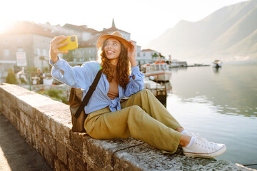 Fototapeta premium Female tourist taking selfie photos on sightseeing. Selfie time. Lifestyle, adventure, nature, active life.