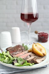 Delicious roasted beef meat, caramelized pear and greens served on table, closeup