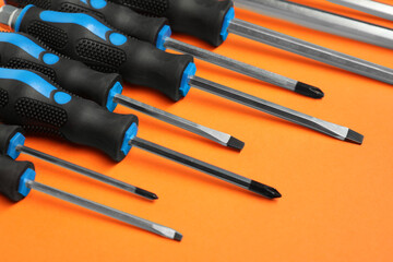 Set of screwdrivers on orange background, closeup
