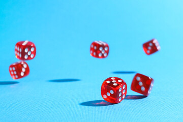 Many red game dices falling on light blue background