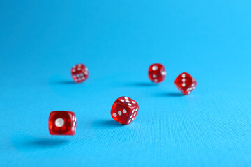 Many red game dices falling on light blue background