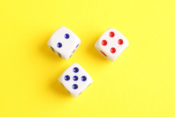 Three white game dices on yellow background, flat lay. Space for text