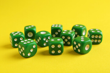 Many green game dices on yellow background, closeup
