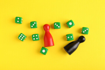 Many green dices and color game pieces on yellow background, flat lay