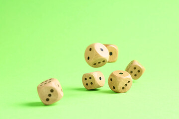 Many wooden game dices falling on green background
