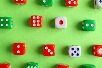 Many color game dices on green background, flat lay