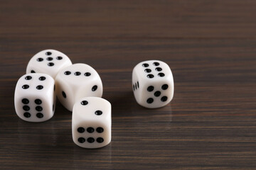 Many white game dices on wooden table, closeup. Space for text