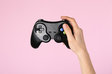 Woman with game controller on pink background, closeup © New Africa