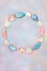 Mother of pearl and sea shell wreath decoration on rainbow sky background. Seaside summer art...