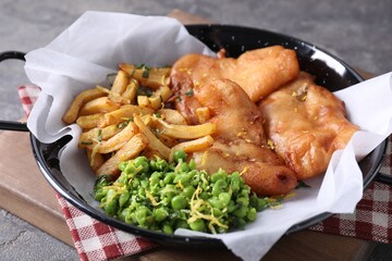 Tasty fish, chips and peas on grey table, closeup