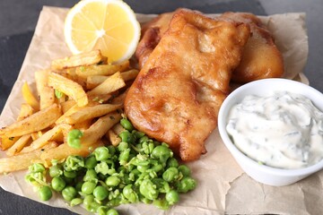 Tasty fish, chips, sauce and peas on table, closeup